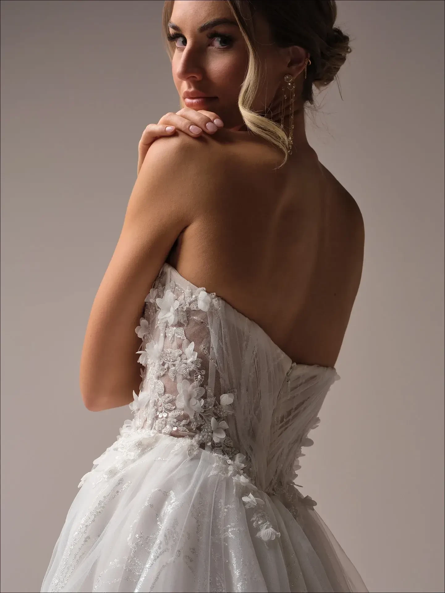 Model is wearing a shimmering A-line dress with a feminine bodice and an elegant open back