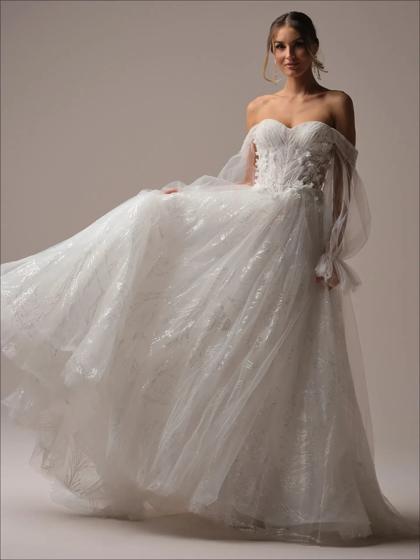 Model is wearing a shimmering A-line dress with a feminine bodice and an elegant open back