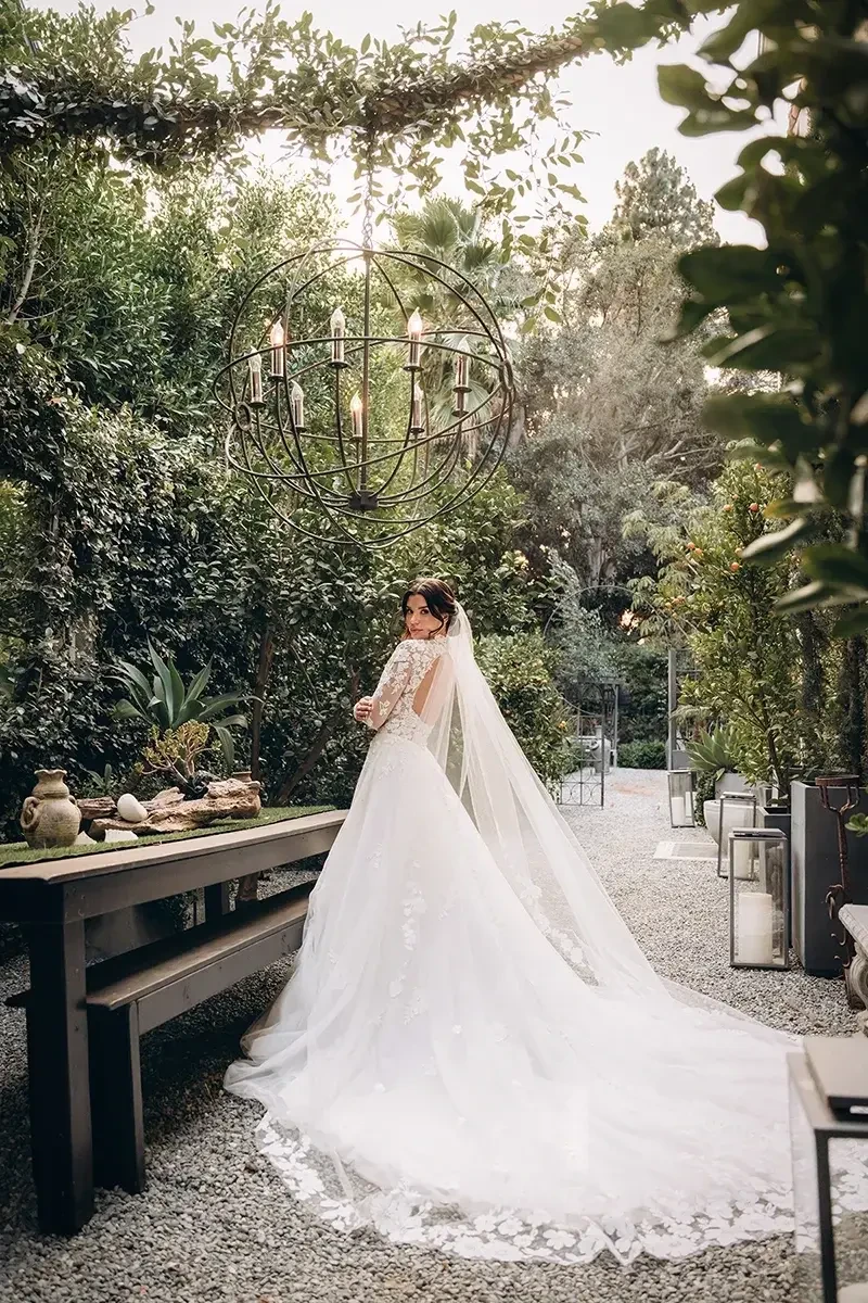 Model is wearing a romantic ball gown with a high neckline, sheer bodice, and an open lace keyhole back for a dramatic finish.